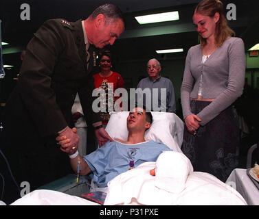 Des Marine Corps, General James L. Jones, Stifte die Purple Heart Medaille auf Marine Corporal Christopher Krämer am Walter Reed Army Krankenhaus am 25. Dezember 2001. Der junge Unteroffizier verlor seinen Fuß nach tritt auf eine Landmine in Kandahar, Afghanistan, letzte Woche und war am Walter Reed Für weitere Operation und Genesung. Auf der rechten Seite in der Verlobten des Corporal. Stockfoto