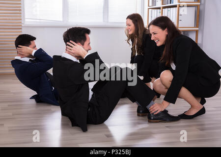 Glückliche junge Unternehmerinnen Unterstützung der männlichen Kollegen während einer Übung am Arbeitsplatz Stockfoto