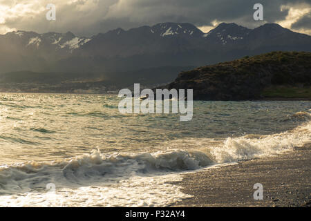 Eine Welle endet am Strand von Playa Larga. Im Hintergrund sehen Sie die schnell wachsenden, touristischen Stadt Ushuaia. Stockfoto