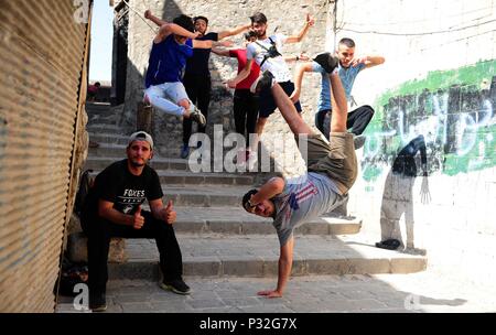 Aleppo, Syrien. 8. Juni 2018. Junge Syrische parkour Spieler führen eine koordinierte Sprung in der weitgehend zerstörten Teil der Stadt Aleppo, nördliches Syrien, am 8. Juni 2018. Mit ihren atemberaubenden Flips und springen Stunts, einer Gruppe junger Syrer bringt wieder Leben in die zerstörte Teile von Aleppo Stadt mit ihrer elektrisierenden Parkour Leistung. Um mit der Funktion: Junge Syrer beleben das Leben in Ruinen der Altstadt von Aleppo mit elektrisierenden Parkour Leistung. Credit: Ammar Safarjalani/Xinhua/Alamy leben Nachrichten Stockfoto