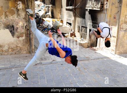 Aleppo, Syrien. 8. Juni 2018. Junge Syrische parkour Spieler durchführen, Front- und Backflips in der weitgehend zerstörten Teil der Stadt Aleppo, nördliches Syrien, am 8. Juni 2018. Mit ihren atemberaubenden Flips und springen Stunts, einer Gruppe junger Syrer bringt wieder Leben in die zerstörte Teile von Aleppo Stadt mit ihrer elektrisierenden Parkour Leistung. Um mit der Funktion: Junge Syrer beleben das Leben in Ruinen der Altstadt von Aleppo mit elektrisierenden Parkour Leistung. Credit: Ammar Safarjalani/Xinhua/Alamy leben Nachrichten Stockfoto