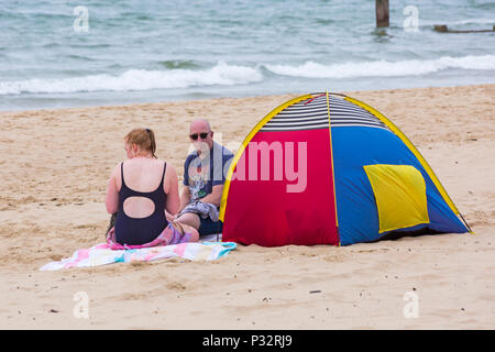 Bournemouth, Dorset, Großbritannien. 17. Juni 2018. UK Wetter: breezy Tag an Alum Chine Beach, nicht davon abhalten, die Besucher zum Meer gehen. Paar mit Zelt sitzen auf Sand. Credit: Carolyn Jenkins/Alamy leben Nachrichten Stockfoto