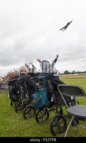 Weltkrieg zwei Veteranen winken zu einem vintage Royal Air Force Lancaster Bomber, wie es über dem Kopf an einem Veteranen feier Veranstaltung Halfpenny Green Airfield in England fliegt. Stockfoto