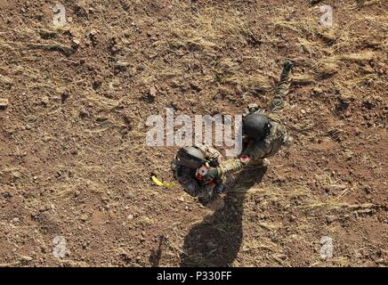 Us-Armee Sgt. Jorge Vasquez, ein Flug medic zu Unternehmen C zugeordnet, 1. Allgemeine Unterstützung Aviation Battalion, 111 Aviation Regiment, Task Force Dragon, Signale der Mannschaft Leiter von einem schwebenden HH-60M Black Hawk Hubschrauber heben eine Rettung Sitz mit einem deutschen Soldaten während einer medevac und Hoist Training übung in Erbil, Irak, Jan. 20, 2016 zu beginnen. Diese Schulung wurde durchgeführt, um zu lehren und zu Deutschen vertraut machen, Niederländische und Finnische Soldaten mit US-Armee medevac Ausrüstung und Verfahren. Mehr als 60 Koalitionspartner haben sich auf das Ziel der Beseitigung der Bedrohung durch das engagierte Stockfoto