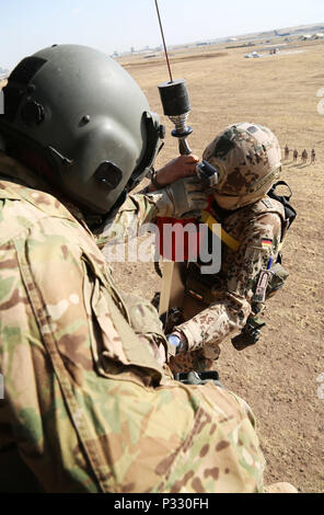 Us-Armee Sgt. Jared Belisle, eine Crew Chief zu Unternehmen C zugeordnet, 1. Allgemeine Unterstützung Aviation Battalion, 111 Aviation Regiment, Task Force Dragon, hilft ein Deutscher Soldat in ein HH-60M Black Hawk Hubschrauber während einer Koalition medevac und Hoist Training übung in Erbil, Irak, Nov. 20, 2016. Diese Schulung wurde durchgeführt, um zu lehren und zu Deutschen vertraut machen, Niederländische und Finnische Soldaten mit US-Armee medevac Ausrüstung und Verfahren. Mehr als 60 Koalitionspartner haben sich auf das Ziel der Beseitigung der Bedrohung durch den Islamischen Staat im Irak und der Levante verpflichtet und haben dazu beigetragen, Stockfoto
