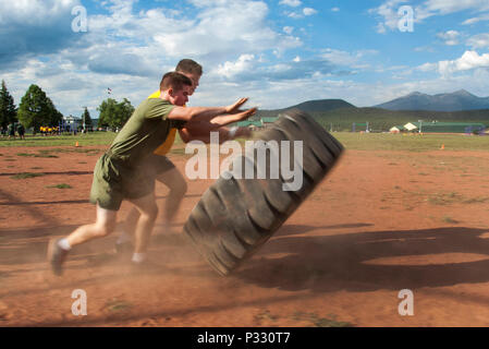 Midshipman-Kandidaten drehen Reifenflips um einen Baseballdiamanten, um Punkte an der Reifenstation während des gemeinsamen NSO-Wettbewerbs in Camp Navajo, Arizona, zu sammeln. Teams führen Running, Liegestütze, Pull-ups, Sit-ups, Squats, und fordern Sie Kursübungen in Rotation heraus. Das NROTC-NSO-Programm der University of Arizona legt den Schwerpunkt auf Führung, körperliche Fitness, Teamarbeit, militärische Disziplin, Widerstandsfähigkeit, und Vorbereitung auf die Inbetriebnahme des Offiziers innerhalb einer strukturierten Trainingswoche. Stockfoto