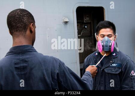 Pazifik (Aug. 29, 2016) Rumpf Techniker 3. Klasse Brandon Dancel, von Everett, Washington, hat Rauch ihn geblasen, während er einen Respirator fit Test führt an Bord des amphibious Transport dock Schiff USS Green Bay LPD (20). Green Bay, Teil der Bonhomme Richard Expeditionary Strike Group, ist in den USA der 7. Flotte Bereich für Maßnahmen zur Erhöhung der Sicherheit und Stabilität in der Indo-Asia-Pazifik-Region. (U.S. Marine Foto von Mass Communication Specialist 1. Klasse Chris Williamson/Freigegeben) Stockfoto