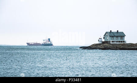 Winzigen blauen Leuchtturm auf schwedische Küste mit grossen Boot auf Hintergrund Stockfoto