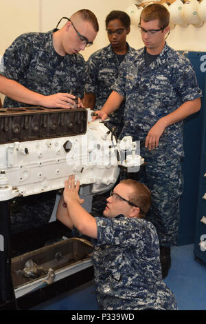 Seaman Jakob Pruett (oben links), Petty Officer 3rd Class Raquel Alvarado, Petty Officer 1st Class Gregory Hermann und Petty Officer 1st Class Robin Mosely (unten Mitte) die Nummer 1 der Kolben in den Motorblock eines Marine Diesel Motor gleiten an SERMC. Enginemen an SERMC bieten Ingenieur- und technische Dienstleistungen für die Instandhaltung und modernation der Schiffe und Boote der Flotte Verantwortungsbereich. Stockfoto