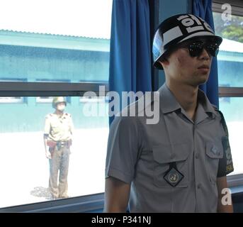 Ein koreanischer Soldat steht Wache im Inneren der Hauptkonferenz Gebäude zwischen Nord- und Südkorea 12.08.16, den Schutz der Soldaten der 1. Gepanzerten Brigade Combat Team, 1.Kavallerie Division, die im Gebäude erhielten einen Einblick in die Verhandlungen zwischen den Vereinten Nationen und Nordkorea. Vor dem Fenster, eine nordkoreanische Soldaten wacht. (U.S. Armee Foto von SPC. Jeremy Wiederverwendung, 2nd Battalion, 8th Cavalry Regiment, 1st Armored Brigade Combat Team, 1.Cav. Div.) Stockfoto