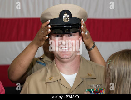 NORFOLK, Virginia (12. Juni 2018) - - Senior Chief Aviation Elektroniker Phillip Sawicki, von den Niagara Falls, New York, zu USS Gerald R. Ford's (CVN 78) Aviation intermediate maintenance Abteilung zugewiesen, wird vom Master Chief Avionik Techniker Tinesha Truppe während eines Senior Chief Petty Officer pinning Zeremonie in den Hangar bay abgedeckt. Ford hatte 14 Chief Petty Officers in den Rang eines Senior Chief Petty Officer. (U.S. Marine Foto von Mass Communication Specialist 3. Klasse Ryan Carter) Stockfoto