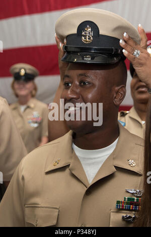 NORFOLK, Virginia (12. Juni 2018) - - Senior Chief Luftfahrt Elektronik Techniker Paul Glenn, aus Atlanta, USS Gerald R. Ford's (CVN 78) Aviation intermediate maintenance Abteilung zugewiesen, wird vom Master Chief Avionik Techniker Tinesha Truppe während eines Senior Chief Petty Officer pinning Zeremonie in den Hangar bay abgedeckt. Ford hatte 14 Chief Petty Officers in den Rang eines Senior Chief Petty Officer. (U.S. Marine Foto von Mass Communication Specialist 3. Klasse Connor D. Loessin) Stockfoto