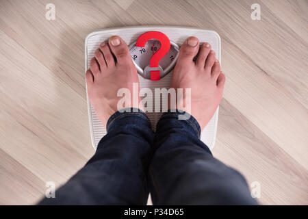 Die Füße stehen auf der Waage mit roten Fragezeichen Zeichen Stockfoto