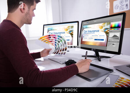 Seitenansicht eines jungen männlichen Designer halten bunte Swatch Arbeiten am Computer im Büro Stockfoto