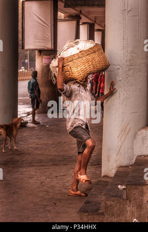 MUMBAI, INDIEN - Januar 29, 2017: unbekannter Mann carryng Gewicht auf seinem Kopf - ein Eimer voller frischer Fisch Stockfoto