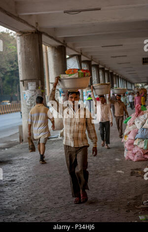 MUMBAI, INDIEN - Januar 29, 2017: unbekannter Mann carryng Gewicht auf seinem Kopf - ein Eimer voller frischer Fisch Stockfoto