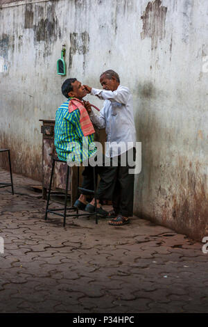 MUMBAI, INDIEN - Januar 29, 2017: eine Straße, Friseur rasiert ein Kunde auf Straßen von Mumbai Stockfoto