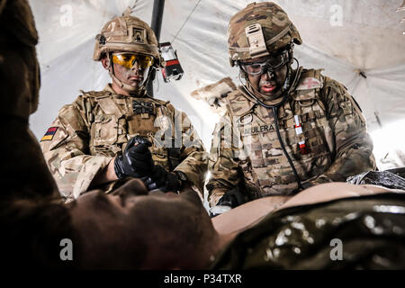 Us-Armee SPC. Roberto Aguilera (rechts), Houston, Texas Eingeborener, combat Medic mit 287 Military Police Company, 89th Military Police Brigade, und eine britische Armee Soldat (links) mit 1 Queen's Dragoon Guards, erste Hilfe Training auf einem US-Soldat während der Übung Puma 2 mit Battle Group Polen führen an Bemowo Piskie, Polen am 13. Juni 2018 im Rahmen der Sabre Streik 18. Die diesjährige Übung, die läuft von Juni 3-15, tests Verbündete und Partner aus 19 Ländern auf ihrer Fähigkeit, arbeiten zusammen, um die Aggression in der Region zu verhindern und die Fähigkeit der einzelnen Einheit ihre Desig durchführen zu verbessern. Stockfoto