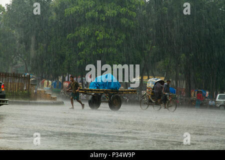 Rikschas und Fahrzeuge auf der Straße bei starkem Regen. Dhaka, Bangladesch. Stockfoto