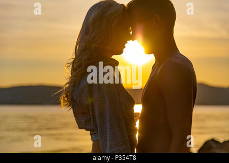 Silhouette von Paar in Liebe umarmen am Strand gegen Sonne Stockfoto