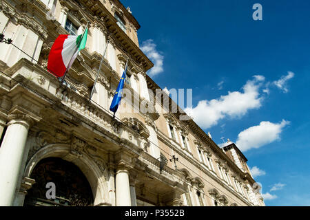 Italienische und EU-Flaggen auf einem Balkon der italienischen Armee Akademie mit blauem Himmel und weißen Wolken. Modena, Italien Stockfoto