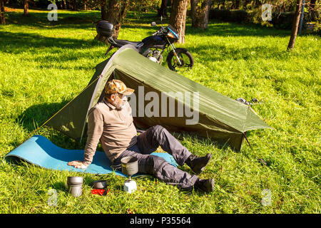 Ältere Touristen Ruhe in der Nähe seiner Hütte im Wald an sonnigen Sommertag Stockfoto