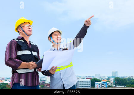 Bauingenieur arbeiten mit seinem Meister zeigen und der Diskussion über die Fortschritte ihrer Projekt auf der Baustelle Stockfoto