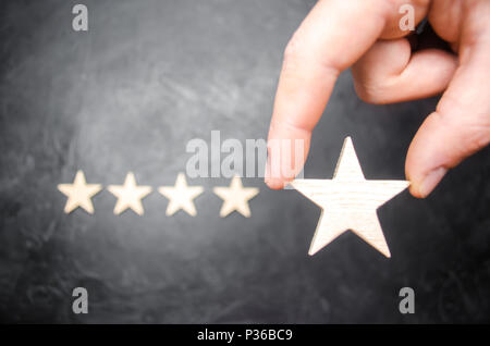 Die Hand des Geschäftsmann im Anzug hält den fünften Stern. Der fünfte Stern erhalten. Das Konzept der Bewertung von Hotels und Restaurants, die Bewertung von cr Stockfoto