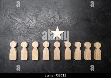 Einem Stern über eine Person, die in einer Reihe von anderen Menschen steht. Holzfiguren. Das Konzept der Ein Zeichen der Unterscheidung, Erfolg, Leistung und Karriere Stockfoto