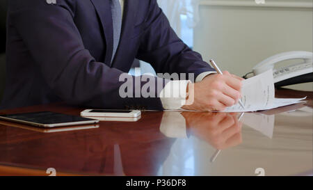 Man Handzeichen ein Papierdokument mit Kugelschreiber. Signatur ist Fake. Stockfoto