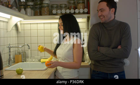 Attraktive Frau waschen Obst und sprechen mit den stattlichen Mann in der Küche Stockfoto