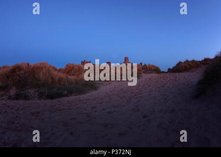 Am Ende des Tages, letzte Licht auf Bamburgh Castle aus Sanddünen, Northumberland, Großbritannien Stockfoto