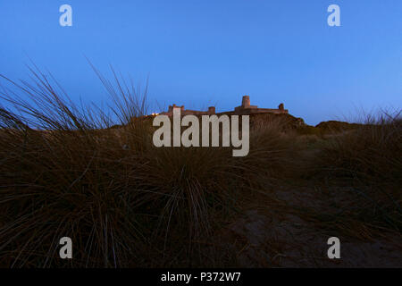 Am Ende des Tages, letzte Licht auf Bamburgh Castle aus Sanddünen, Northumberland, Großbritannien Stockfoto