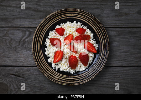 Nützliche Frühstück aus frischen Zutaten: Cornflakes Quark mit Erdbeeren auf einem Holztisch, Ansicht von oben Stockfoto