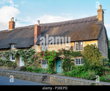 Strohgedeckten Hütten und Kletterrosen in Ebrington, Chipping Campden, Gloucestershire, England Stockfoto