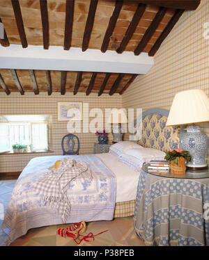 Karierte Tapeten im toskanischen Schlafzimmer mit gepolstertem Kopfteil am Bett mit Blau + Weiß werfen Stockfoto
