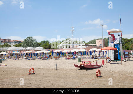 Rettungsschwimmer und Aussichtsturm auf einem sandigen Strand Lido di Venezia, Venedig, Venetien, Italien mit der Blue Moon Aussichtsturm, Pier und Regenschirme mit peo Stockfoto