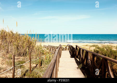 Holzsteg mit Geländer über Dünen zu den Guardamar Strand in Alicante, Spanien. Stockfoto