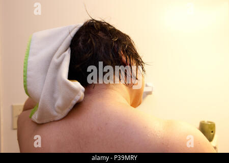 Rückseite des Dunklen den Kopf einer Frau Haar wie Sie reibt es mit einem Handtuch trocken