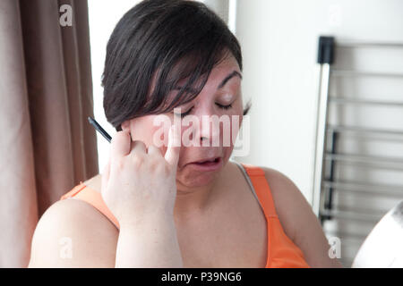 Eine Frau macht einen gequälten Ausdruck nach dem Make-up in den Augen Stockfoto