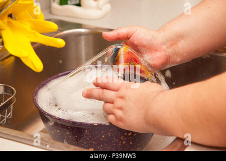In der Nähe der Hände und ein Putzlappen waschen eine Schüssel und Glas Teller in die Spüle Stockfoto