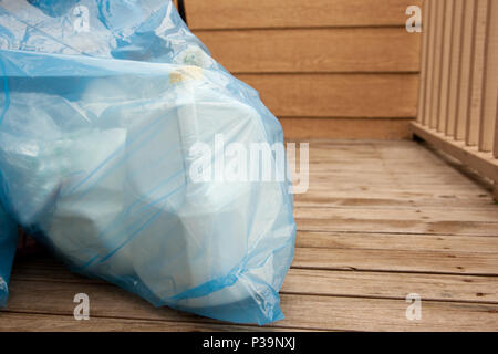 Eine blaue Plastiktüte mit milchtüten ist bereit, recycelt werden, sitzen auf dem Holz terrasse Stockfoto