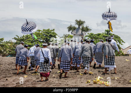 Balinesen in Schwarz und Weiß poleng Kleidung Wandern auf Seseh Strand gekleidet (Pantai Seseh), Bali, Indonesien. Melasti, hinduistischen Zeremonie. Stockfoto