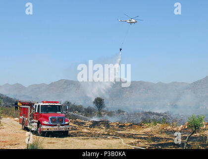 Kreta, Griechenland (23.07.2008) U.S. Navy Feuerwehrmänner arbeiten ein Bürste Feuer in der Nähe des Internationalen Flughafen Chania zu löschen, da eine Griechische M-26 Hubschrauber zur Brandbekämpfung auf den Bereich Wasser fällt von oben. Naval Support Activity (NSA) Souday Bay reagierte auf eine Anfrage auf Unterstützung von lokalen Behörden und versendet 21 Feuerwehrmänner und 5 Einsatzfahrzeuge an der Szene, zusammen mit zwei Seabees und andere Mitarbeiter für Unterstützung und Zusammenarbeit. Stockfoto