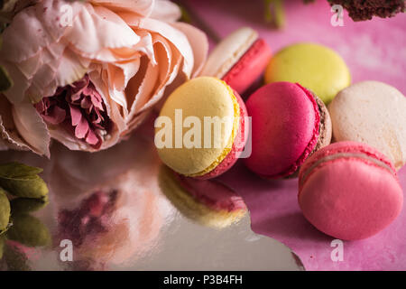 Kuchen Makronen auf rosa Hintergrund. Close up Macaron Dessert auf der Ansicht von oben. Bunte almond Cookies in Pastell rosa, gelben Farben. Vintage toning Stil. Stockfoto