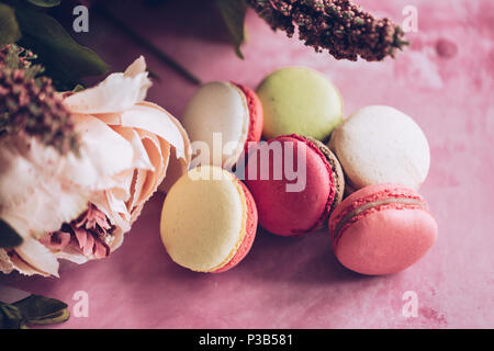 Kuchen Makronen auf rosa Hintergrund. Close up Macaron Dessert auf der Ansicht von oben. Bunte almond Cookies in Pastell rosa, gelben Farben. Vintage toning Stil. Stockfoto
