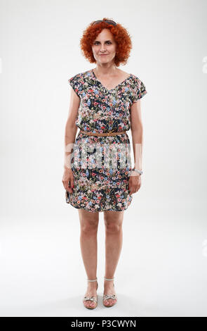 In voller Länge Porträt einer geschweiften rothaarige Frau in geblümten Kleid Stockfoto