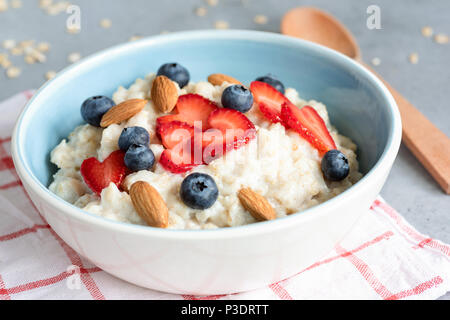 Heiße Haferflocken Haferbrei mit frischen Beeren und Nüsse in eine blaue Schale, Detailansicht. Konzept der gesunden Ernährung, gesund leben, Diät und Fitness Essen Stockfoto