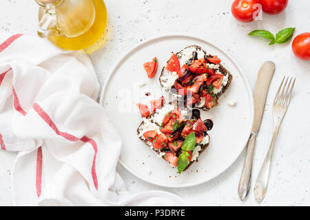 Gesunde italienische Bruschetta mit Tomaten, Basilikum, Fetakäse und Balsamico Essig. Ansicht von oben. Leckere Toasts mit Käse und Tomaten Stockfoto