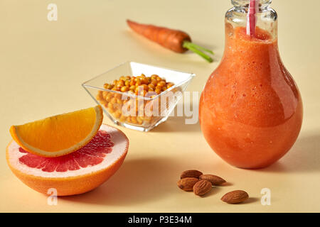 Zitrusfrüchte Gemüse Smoothies mit Mandeln und Sanddorn in einem Glas auf gelbem Papier Hintergrund Stockfoto